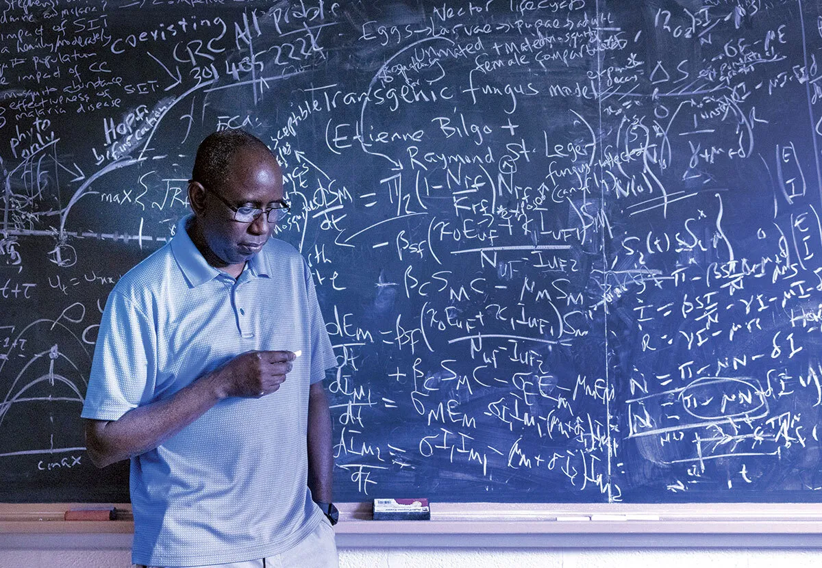 Abba Gumel stands in front of chalkboard with equations written on it