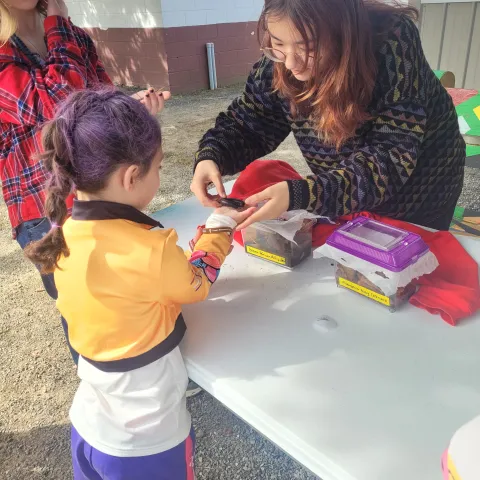 Niina handing a hissing cockroach to children at an outreach event