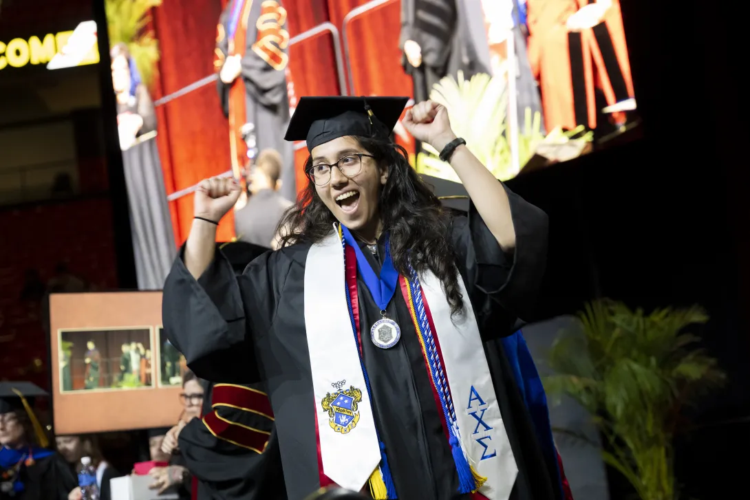 Graduate raising hands in celebration after walking the stage